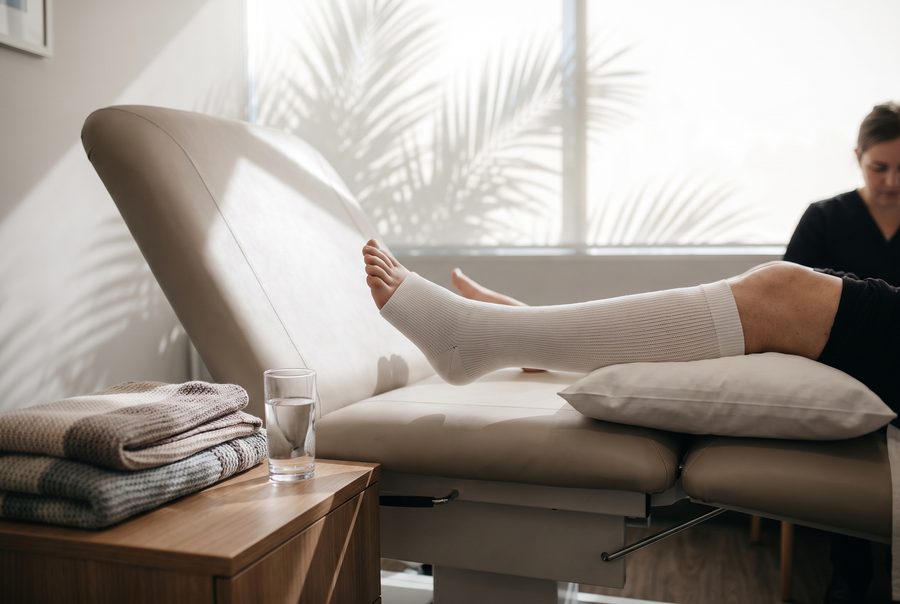 A leg wrapped in a compression bandage resting on a treatment chair after an in-office vein procedure